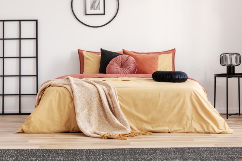 black-round-velvet-pillow-on-yellow-duvet-in-trend-7P9V2J7-Custom.jpg